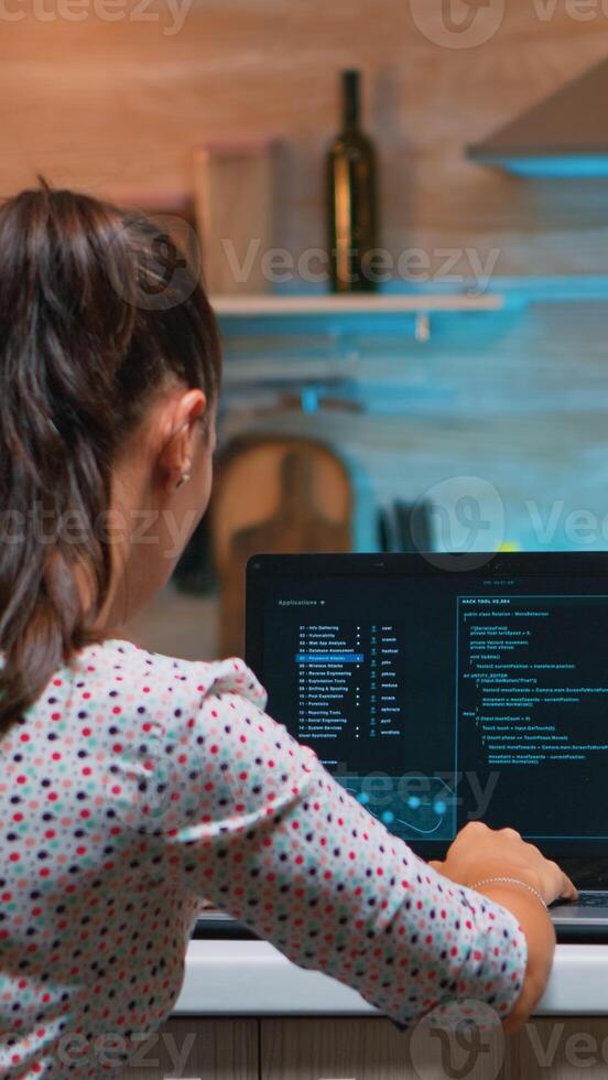 Woman remote thief stealing data from company hacking system from home. Programmer writing a dangerous malware for cyber attacks using performance laptop during midnight. photo