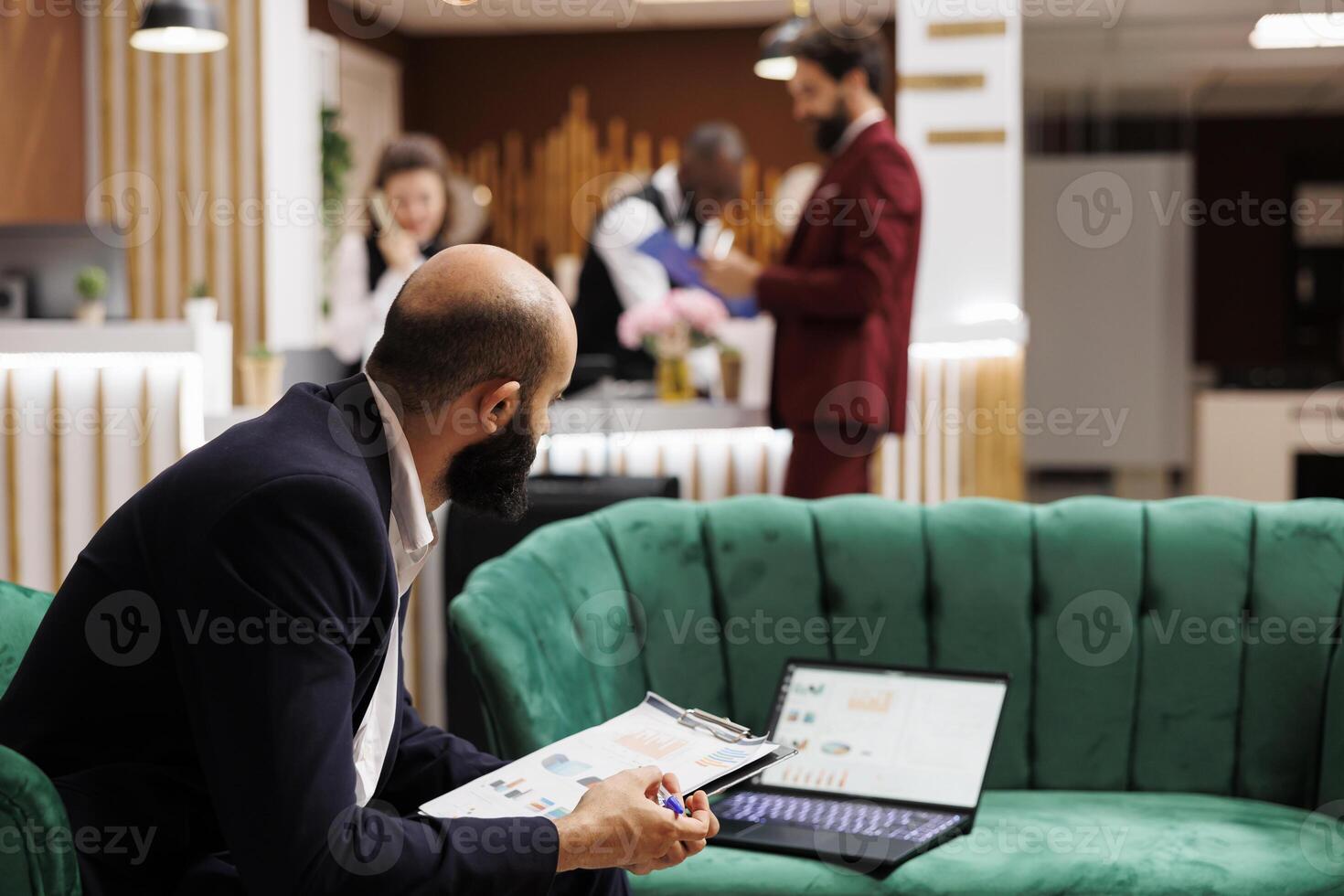 Businessman review documents in lobby at hotel, waiting to do check in procedure and killng time with office work. Entrepreneur attending official meeting and looking over speech notes. photo