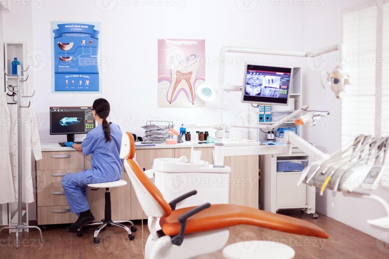 Stomatology office with modern equipment and nurse wearing blue uniform working on computer. photo