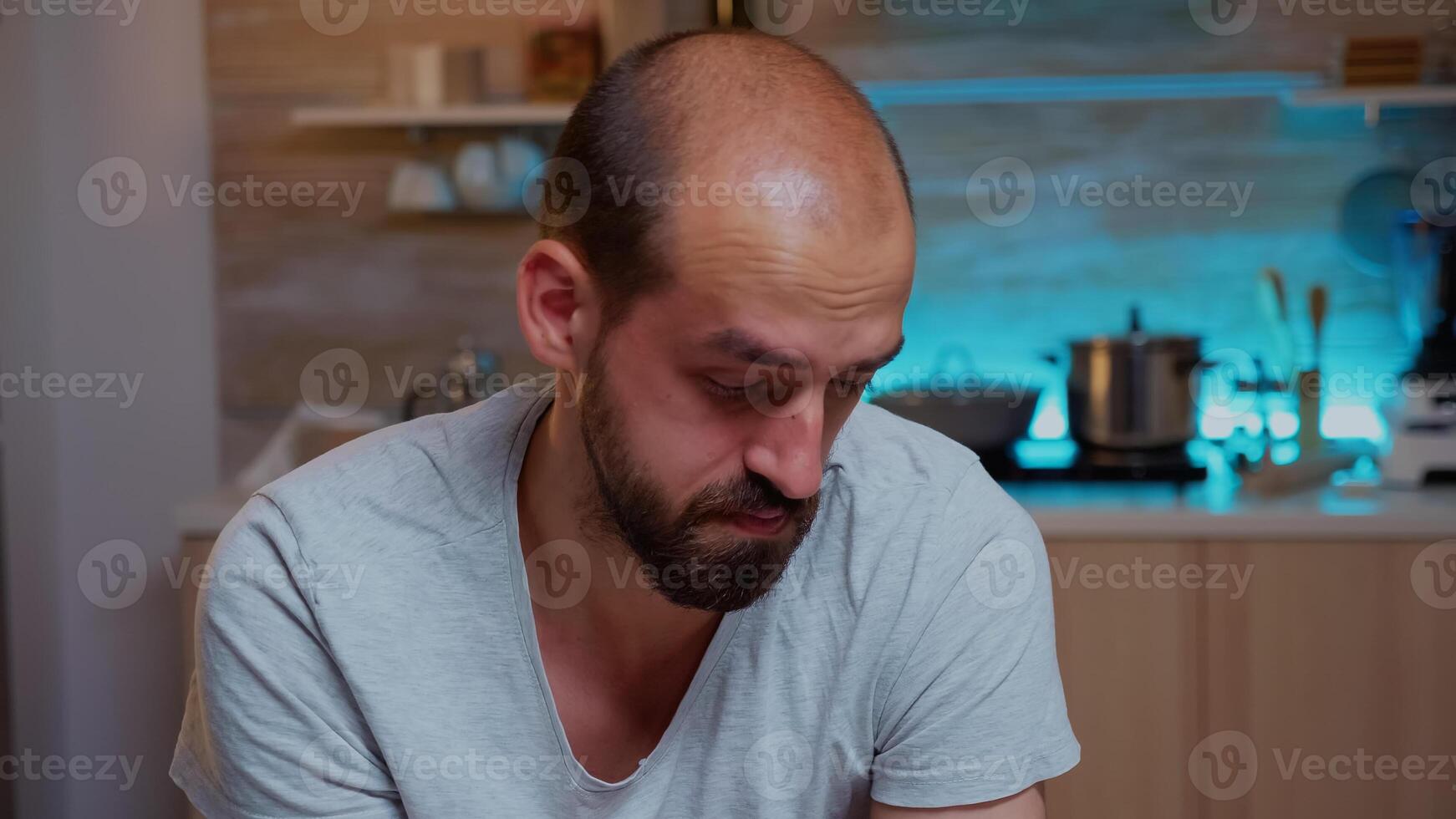 Stressed man working overtime feels eye fatigue after computer work late at night. Portrait of busy focused employee using modern technology network wireless doing overtime for job reading typing photo