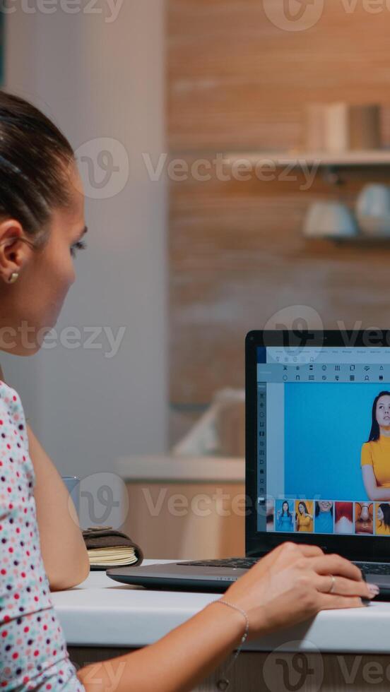 Freelancer retoucher woman working on laptop computer with photo editing software. Professional graphic editor retouching photos of a client during night time in home office on performance pc.