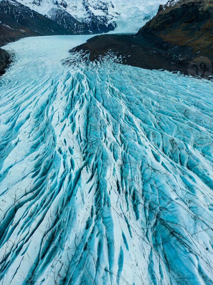 Aerial view of glacier ice cap on wintry region, massive blocks of cracked ice with crevasses in iceland. Spectacular blue diamond shaped rocks creates nordic landscapes, covered frost icebergs. photo