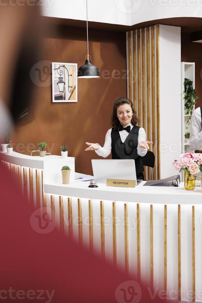 Friendly employee greeting guest in lobby, welcoming businessman at hotel reception for check in process. Front desk staff providing impeccable customer service, corporate business trip. photo