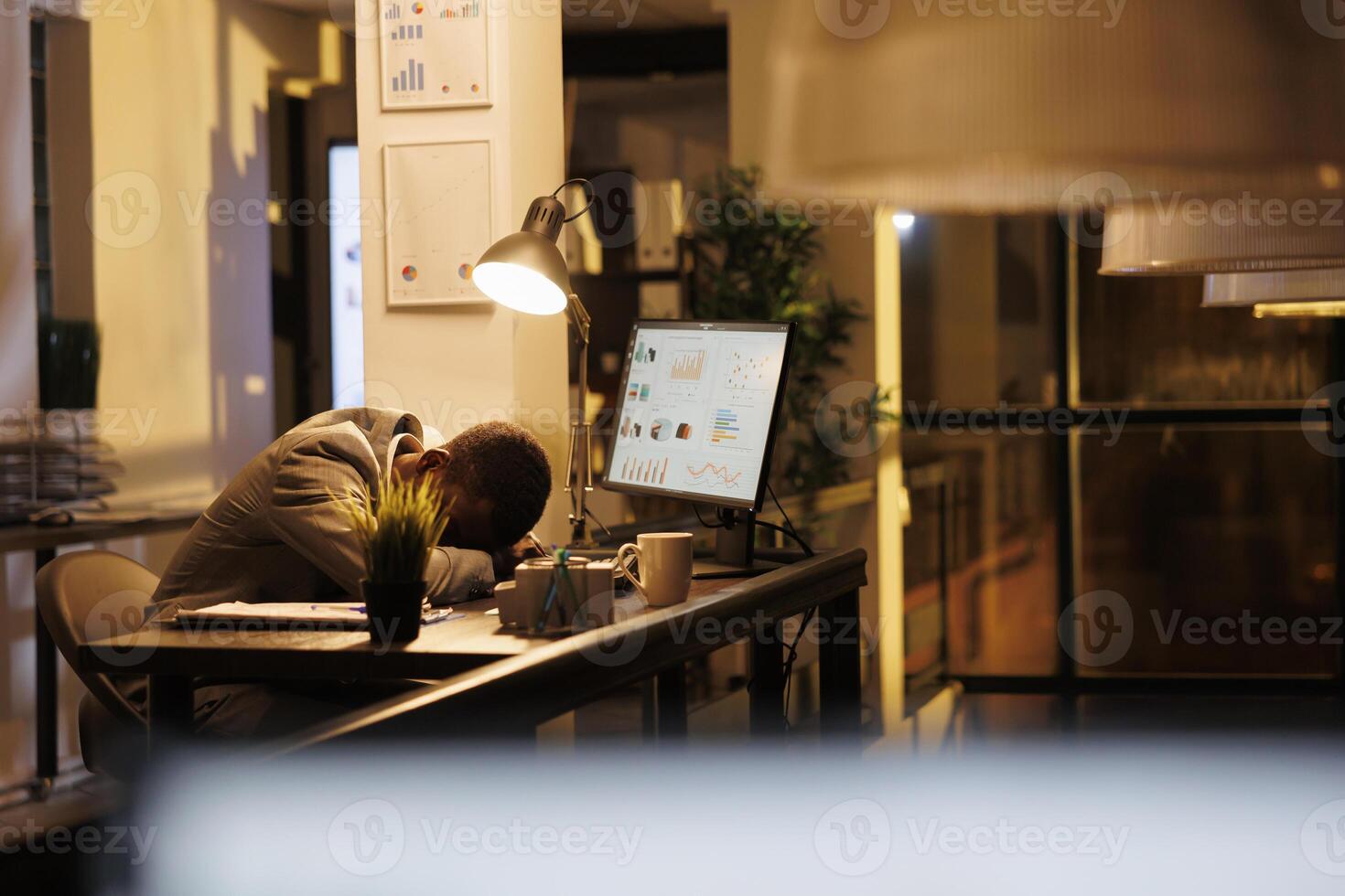 Tired drained entrepreneur sleeping on desk in startup office, workaholic employee falling asleep after finishing financial report. Exhausted african american worker with burnout syndrome resting at work. photo
