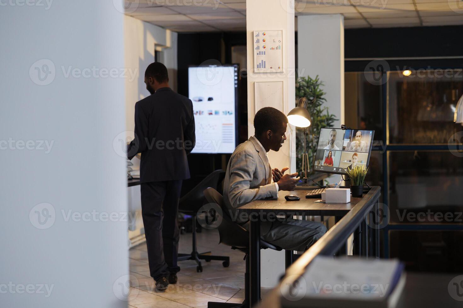 Businessman explaining financial investment graph to remote coworkers during online videocall meeting conference. Diverse remote colleagues working late at night at company strategy photo