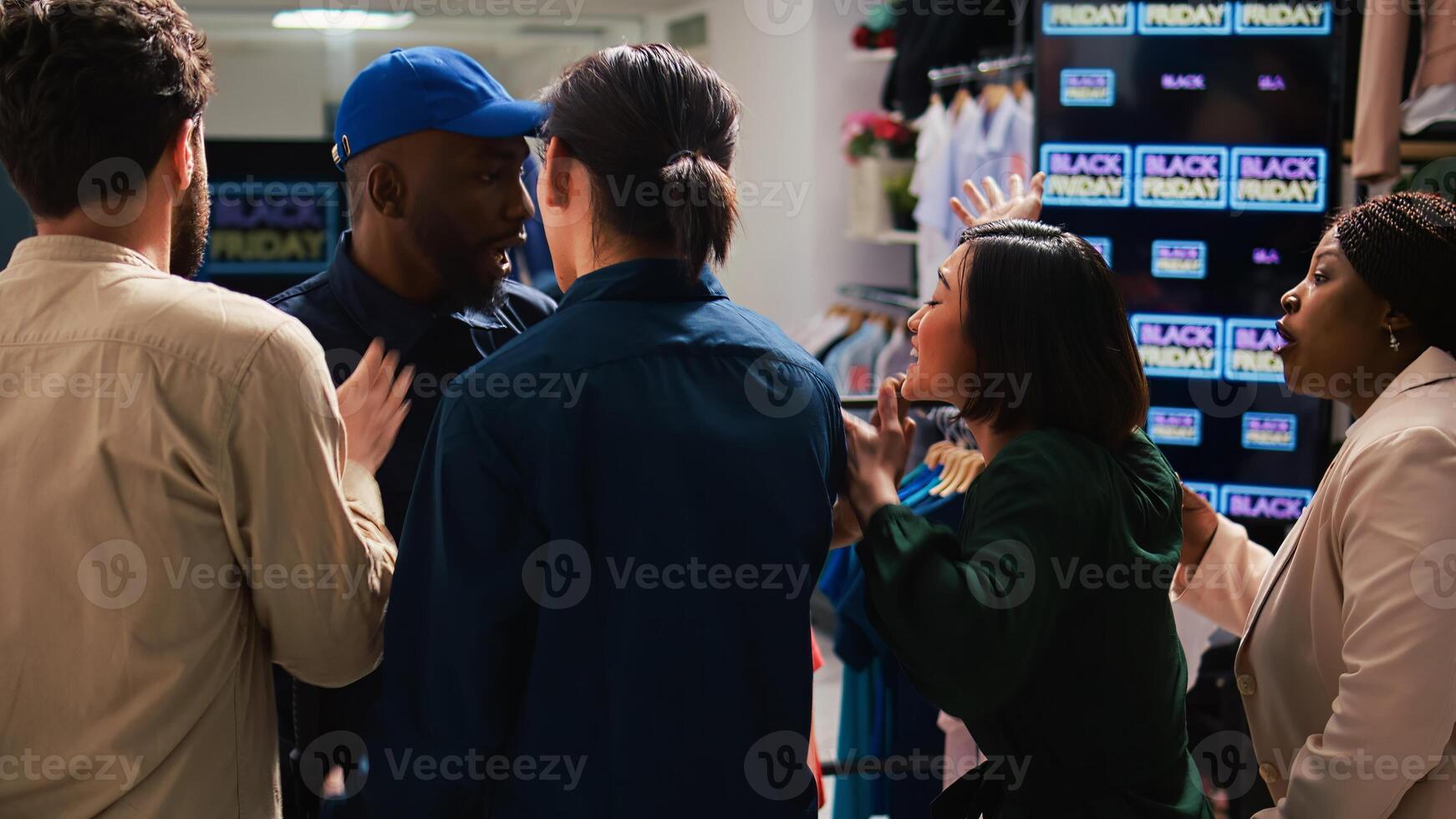 Security officer calms crowd on black friday sales rush, pushing people back and trying to control clothing store entrance. Clients shoppers being impatient, obsessed with cheap prices. photo