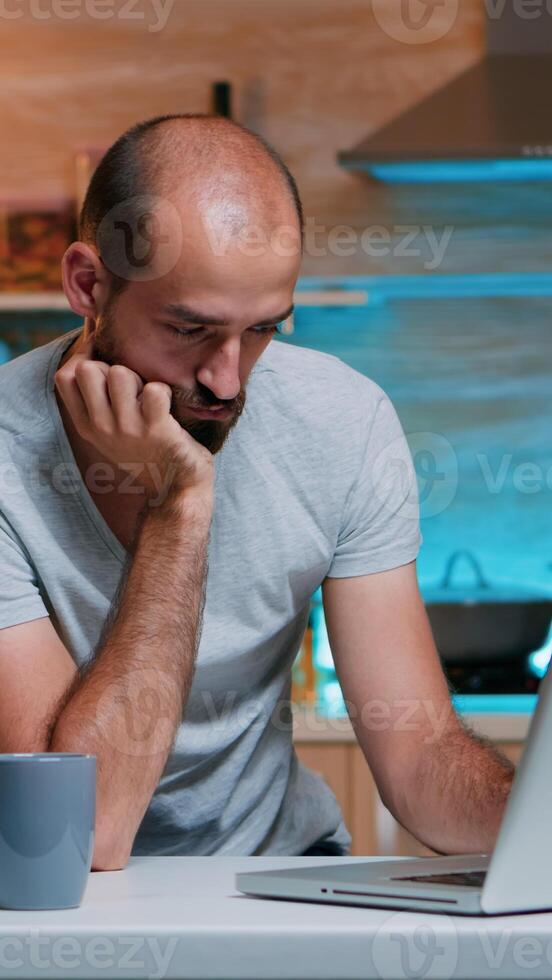 Freelancer stressed from work overload falling asleep looking on laptop sitting in home kitchen. Exhausted remote employee napping on chair waking up working on pc using modern technology network photo