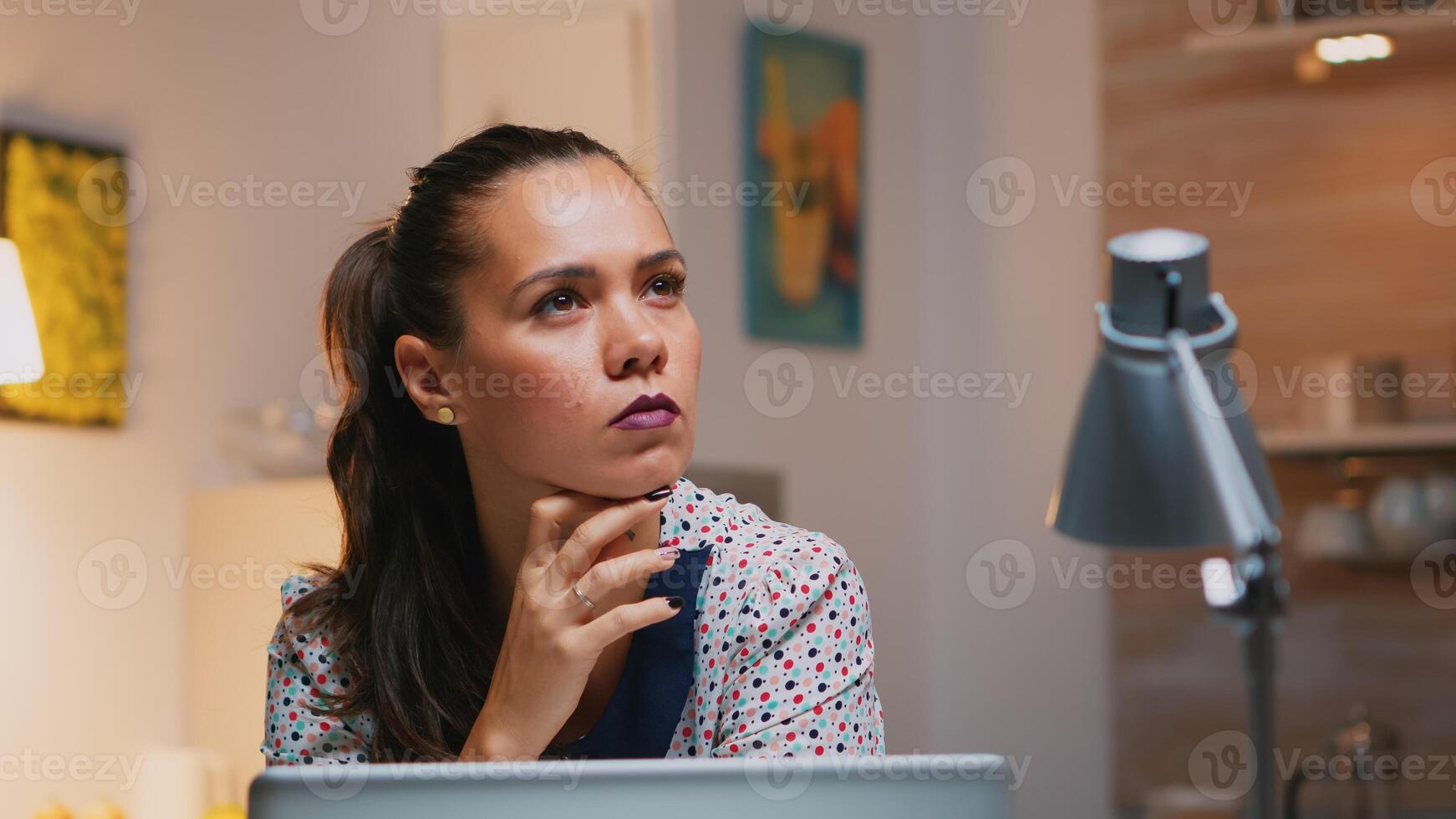 Portrait of businesswoman thinking of email answer working at home sitting on kitchen desk. Close up of busy employee using modern technology network wireless doing overtime reading writing, searching photo