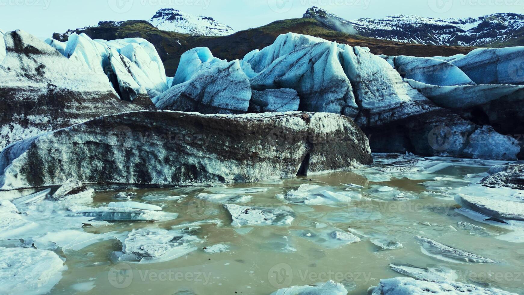 Beautiful vatnajokull glacier drone shot, massive ice blocks and icebergs with blue color. Spectacular icelandic glacier lagoon with snowy mountains and fantastic frozen rocks. Slow motion. photo