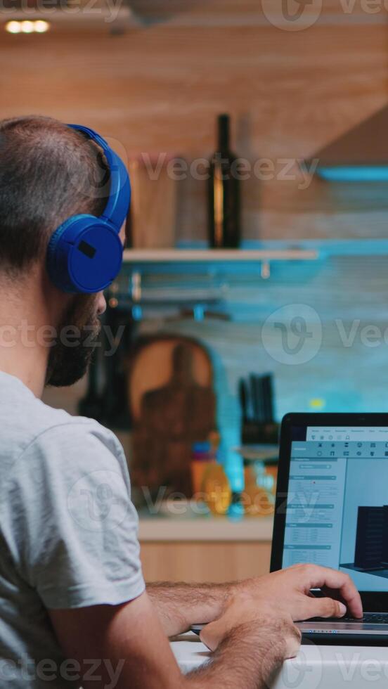 Man designer using cad software to design a 3D concept of buildings working overtime from home. Industrial male employee studying prototype idea on personal computer looking on device display photo