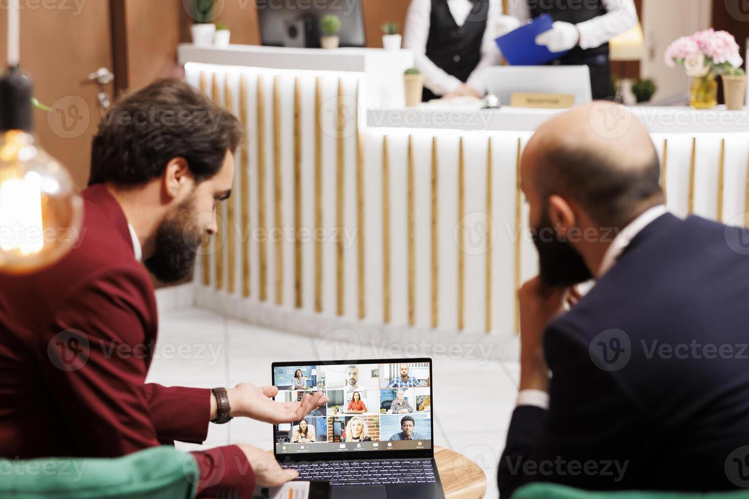 Business partners meet with people on videocall in hotel lobby, attending online teleconference chat to share project ideas, travelling for work. Entrepreneurs working with videoconference. photo