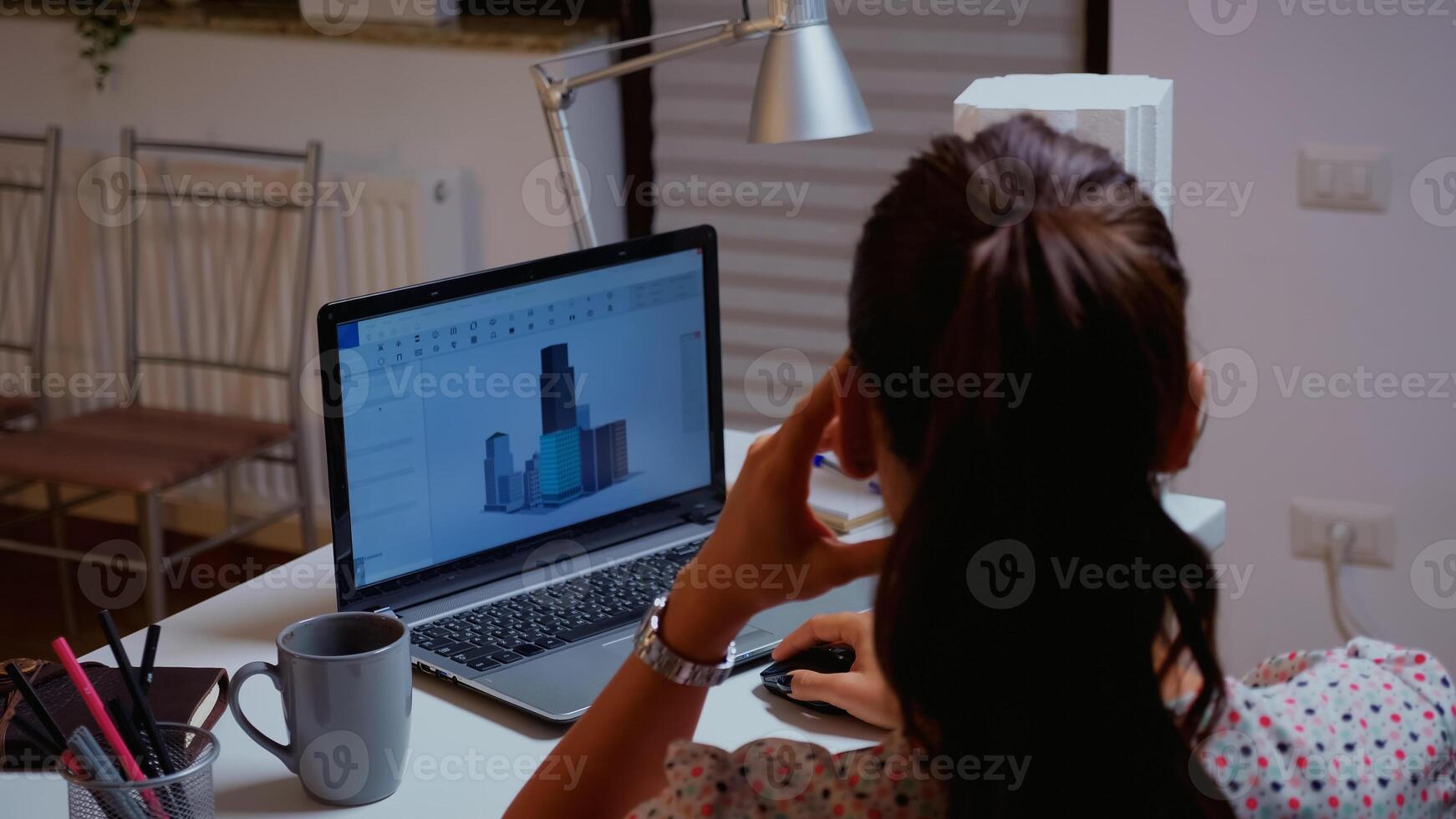 Over the shoulder shot of engineer working with cad software on desktop computer. Designer using a 3D concept of buildings working remotely overtime from home creating and studying new modern model photo