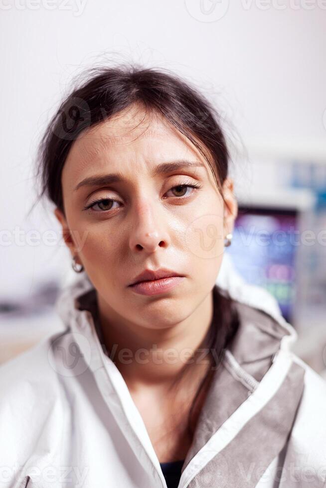 Portrait of tired dentist in protective gear agasint coronavirus looking at camera. Exhausted medical specialist in dentistry cabinet wearing safety equipment during global health crisis. photo