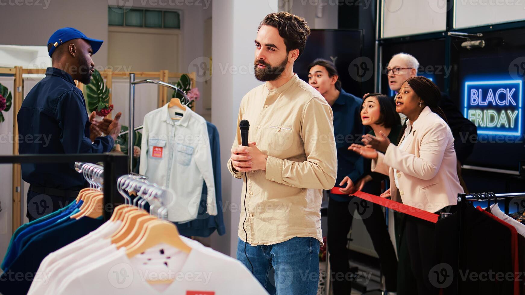 Man reporter recording crazy shoppers at clothing store entrance, broadcasting live black friday news on scene. Male journalist transmitting shopping madness in mall, making media broadcast. photo
