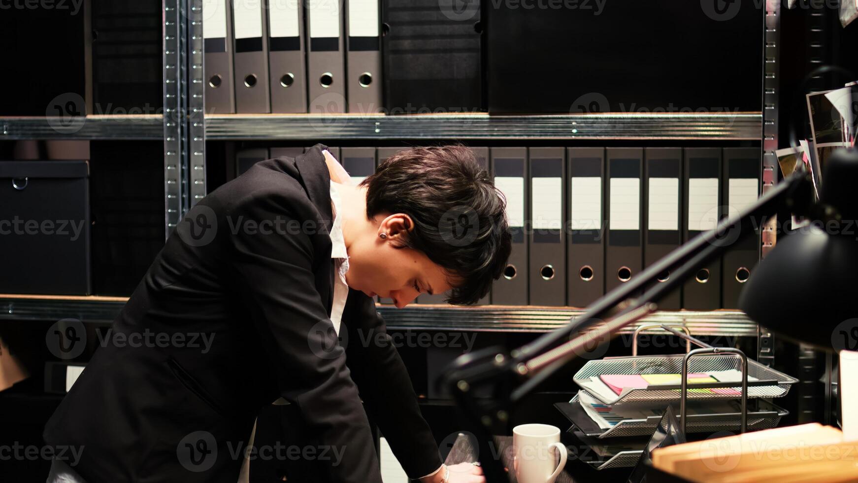 Police agent examines evidence on wall board, following clues to find suspect and solve criminal case. Woman criminologist evaluating proof authenticity, reading classified documents. photo