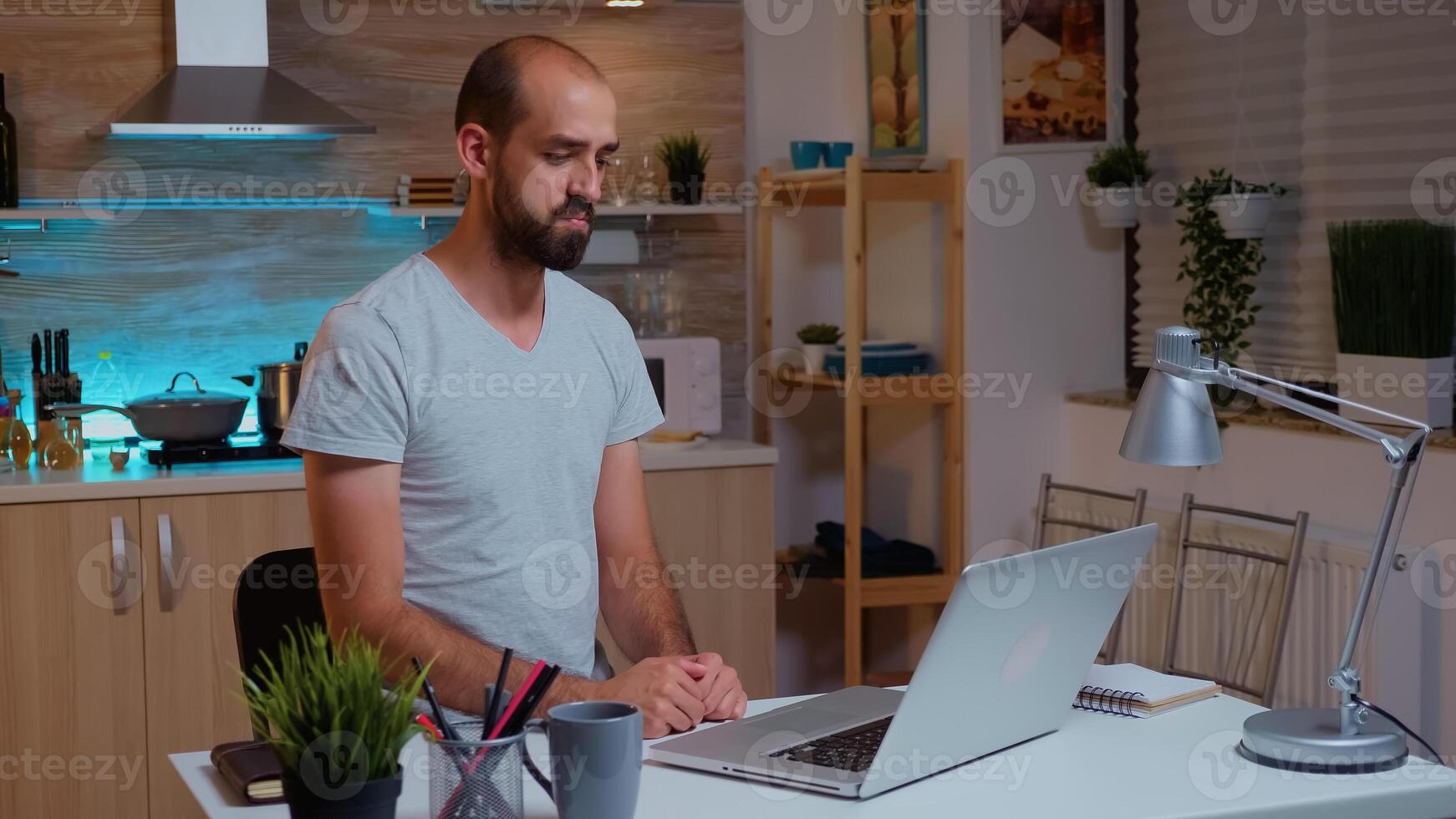 Businessman waving during video conference while working from home at night. Employee using modern technology at midnight doing overtime for job, business, career, network, lifestyle ,wireless. photo