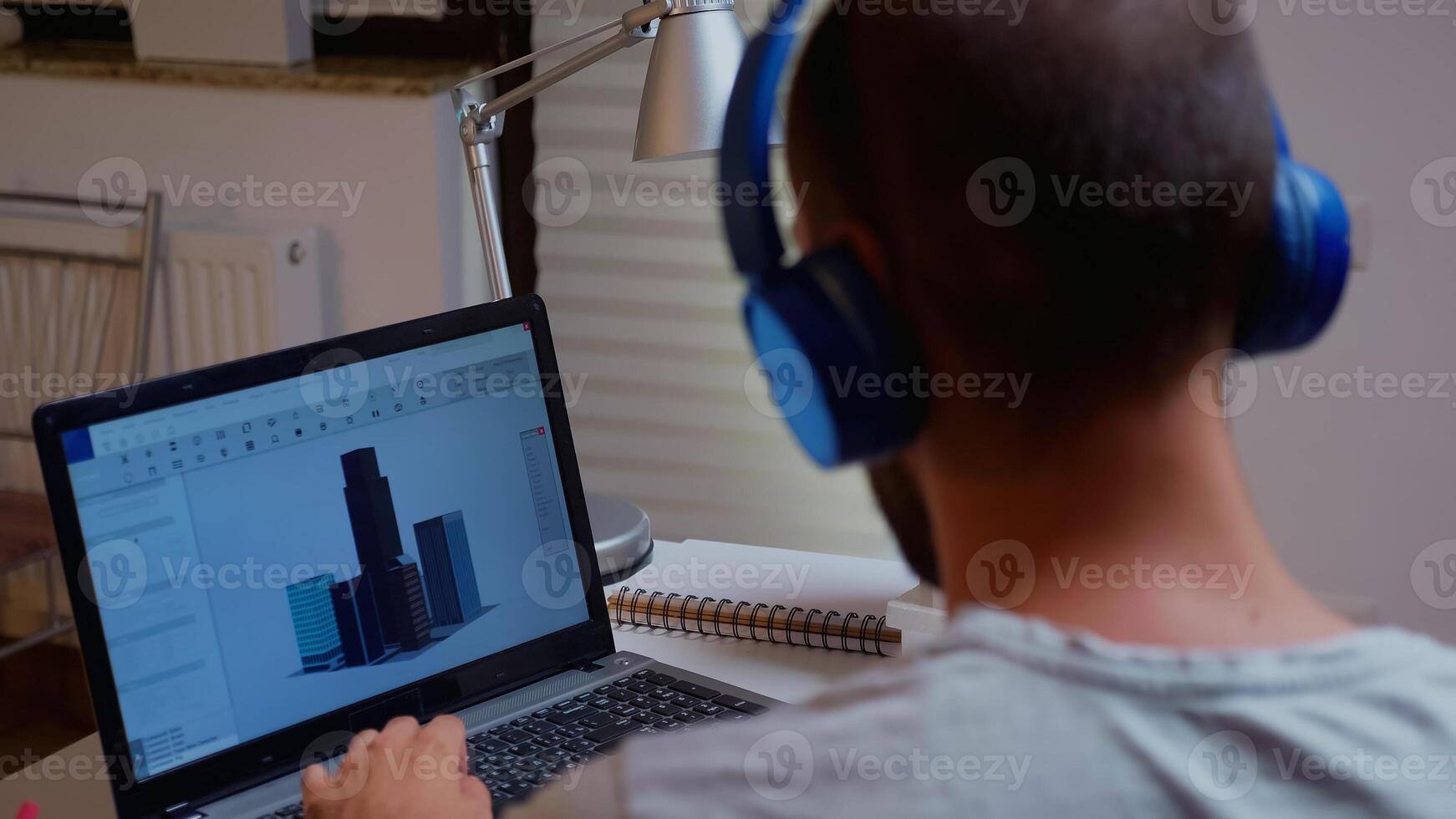 Architect looking at building model on laptop late night time in home office. Industrial employee studying prototype idea on personal computer showing cad software on device display working overtime photo