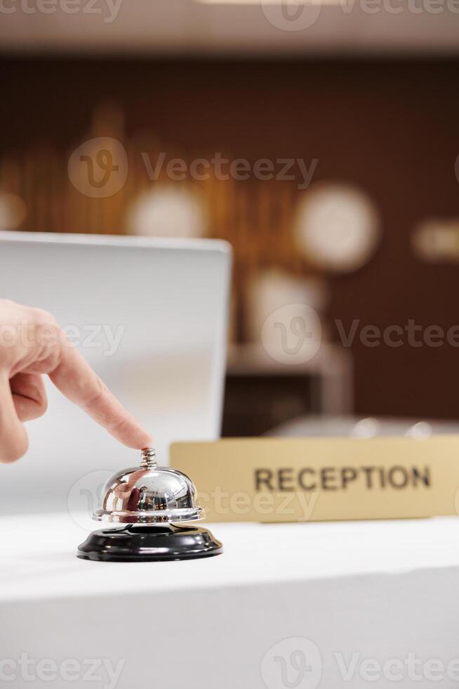 Traveller calling for hotel concierge with service bell on front desk counter, ringing bell to do check in. Hotel guest looking to relax before attending upcoming business meeting. Close up. photo