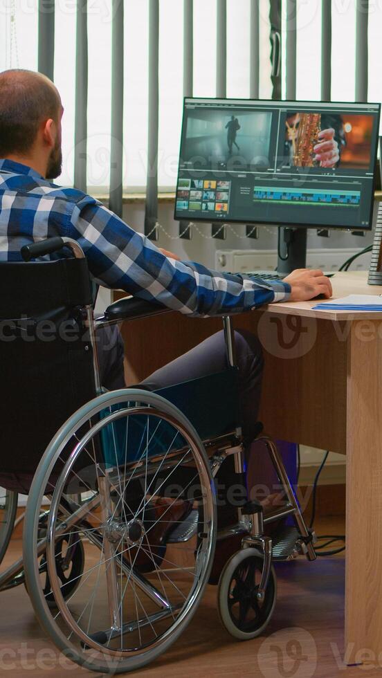 Team of videographers working at video project creating content, man blogger sitting in wheelchair in modern company office. Disabled freelancer editing footage postproduction in studio. photo