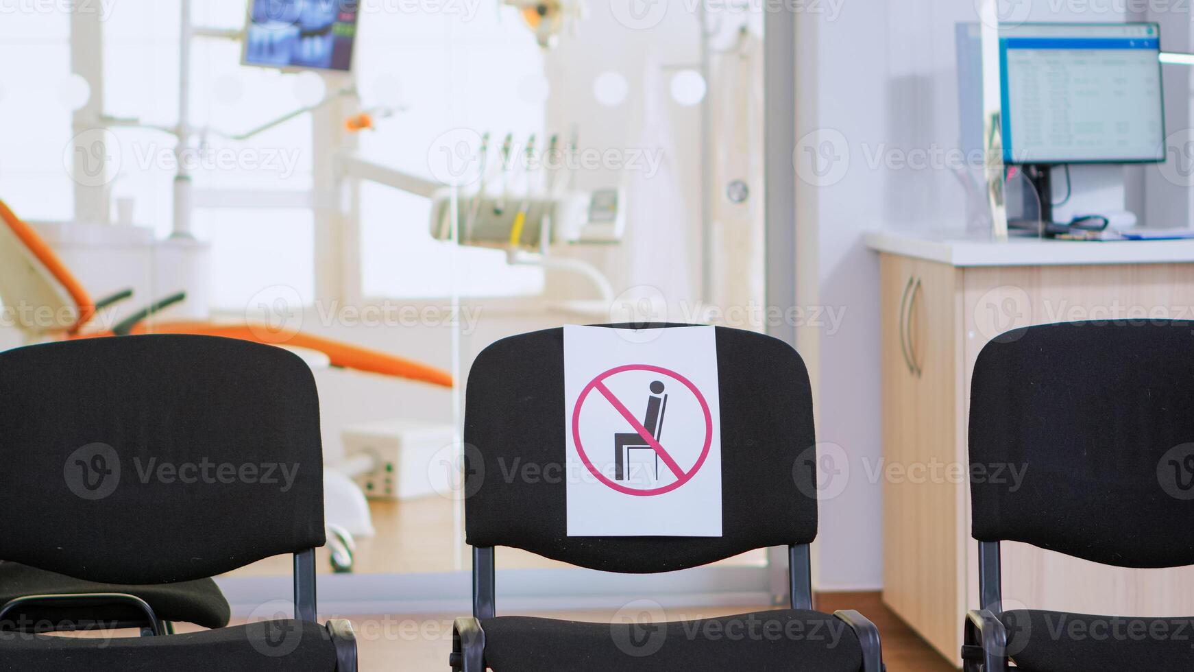 Empty waiting area, stomatology reception with nobody in it with new normal having sign on chair for social distance during covid-19 epidemic. Dental waiting room modern equipped in outbreak time photo