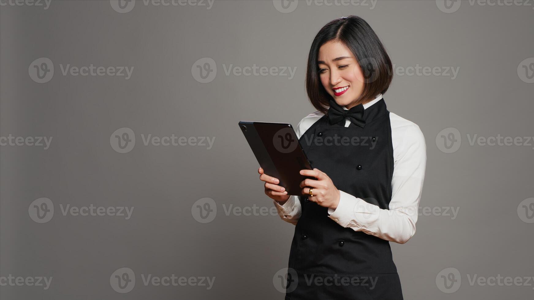 Asian restaurant server checking all table reservations on tablet, browsing through clients information on website. Waitress looking at online webpages to see availability. Camera A. photo
