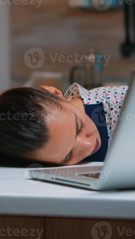 Exhausted overload business woman falling asleep on desk with open laptop monitor while working from home. Busy employee using modern technology network wireless doing overtime sleeping on table. photo