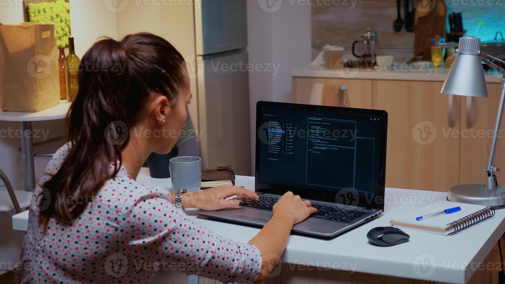 Back view of woman hacker coding a dangerous virus to attack company database in midnight. Programmer writing a dangerous malware for cyber attacks using performance device late at night. photo
