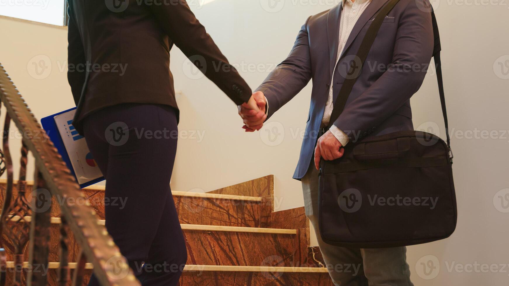 Business woman and executive manager shaking hands while standing on stairs discussing in office building . Group of professional businesspeople working in modern financial workplace. photo