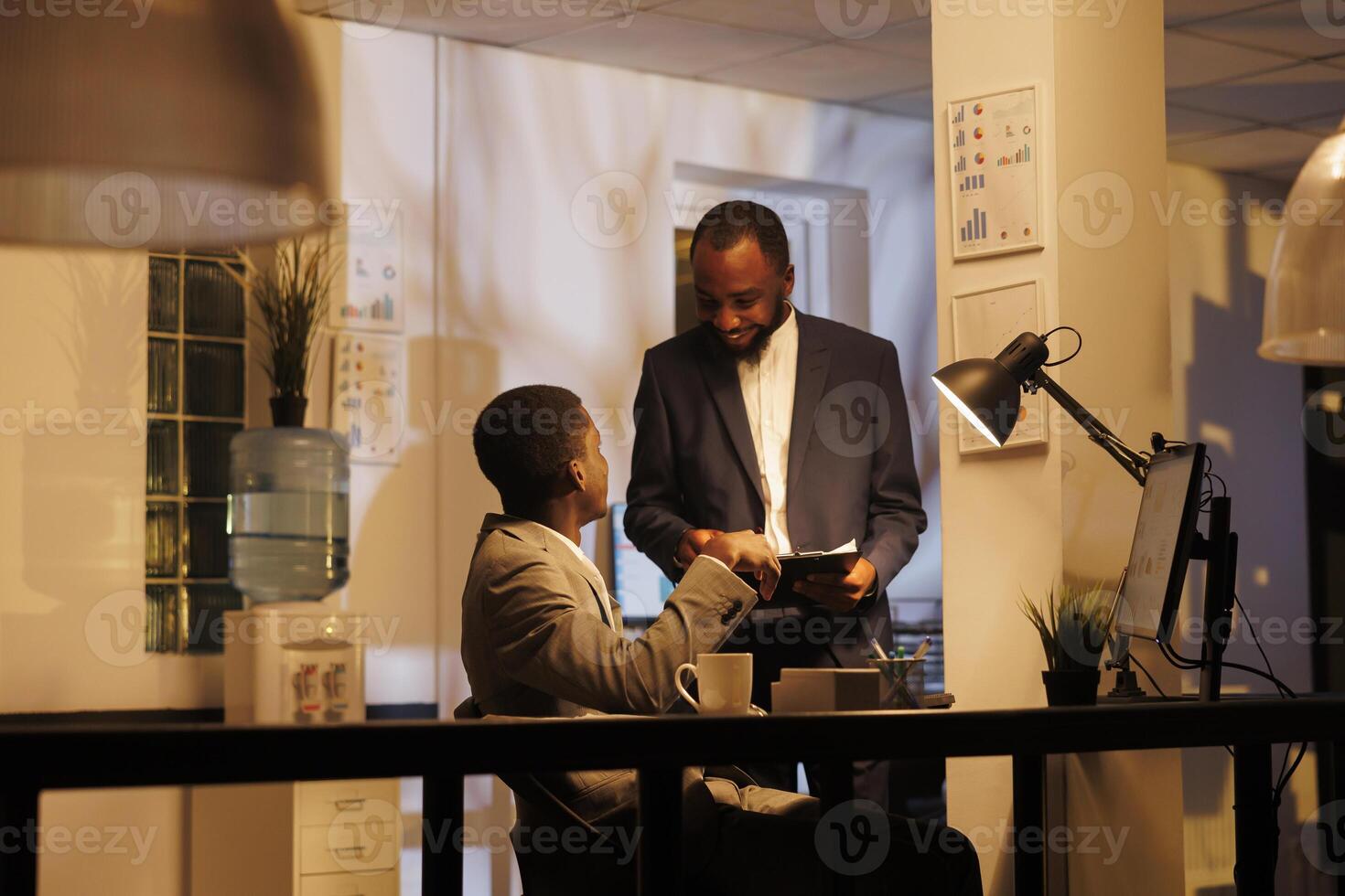 African american businessmen discussing marketing statistics, working at company growth report before start planning investment strategy. Manager showing profit charts to coworker photo