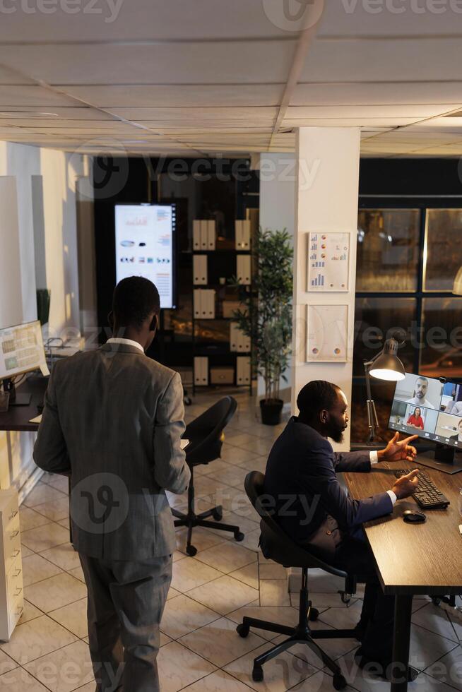 Business team discussing marketing statistics during online videocall meeting conference, working over time at company strategy in startup office. Remote coworkers preparing investment graph photo