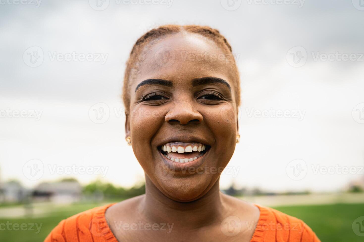 Happy African woman smiling in front of a camera in park photo