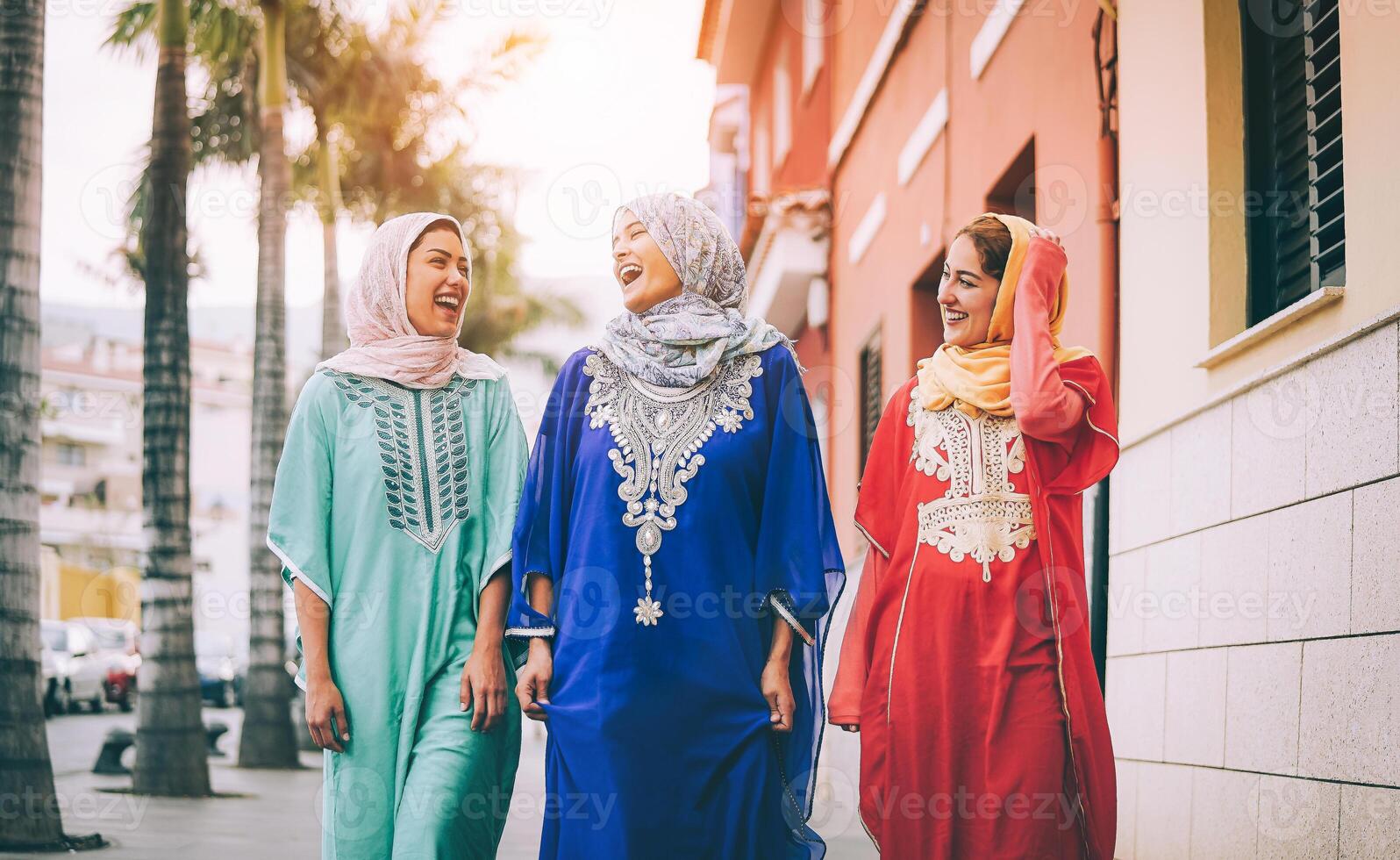 Happy Muslim women walking in the city center - Arabian young girls having fun spending time and laughing together outdoor - concept of people, culture and religion photo