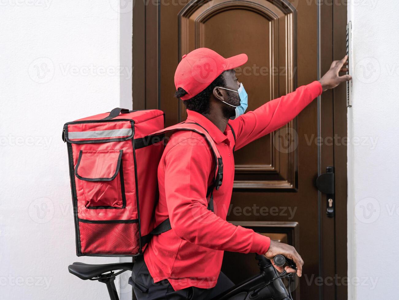 African rider man delivering meal to customers home with electric bicycle while wearing face mask during corona virus outbreak - Ecological fast delivery food concept photo