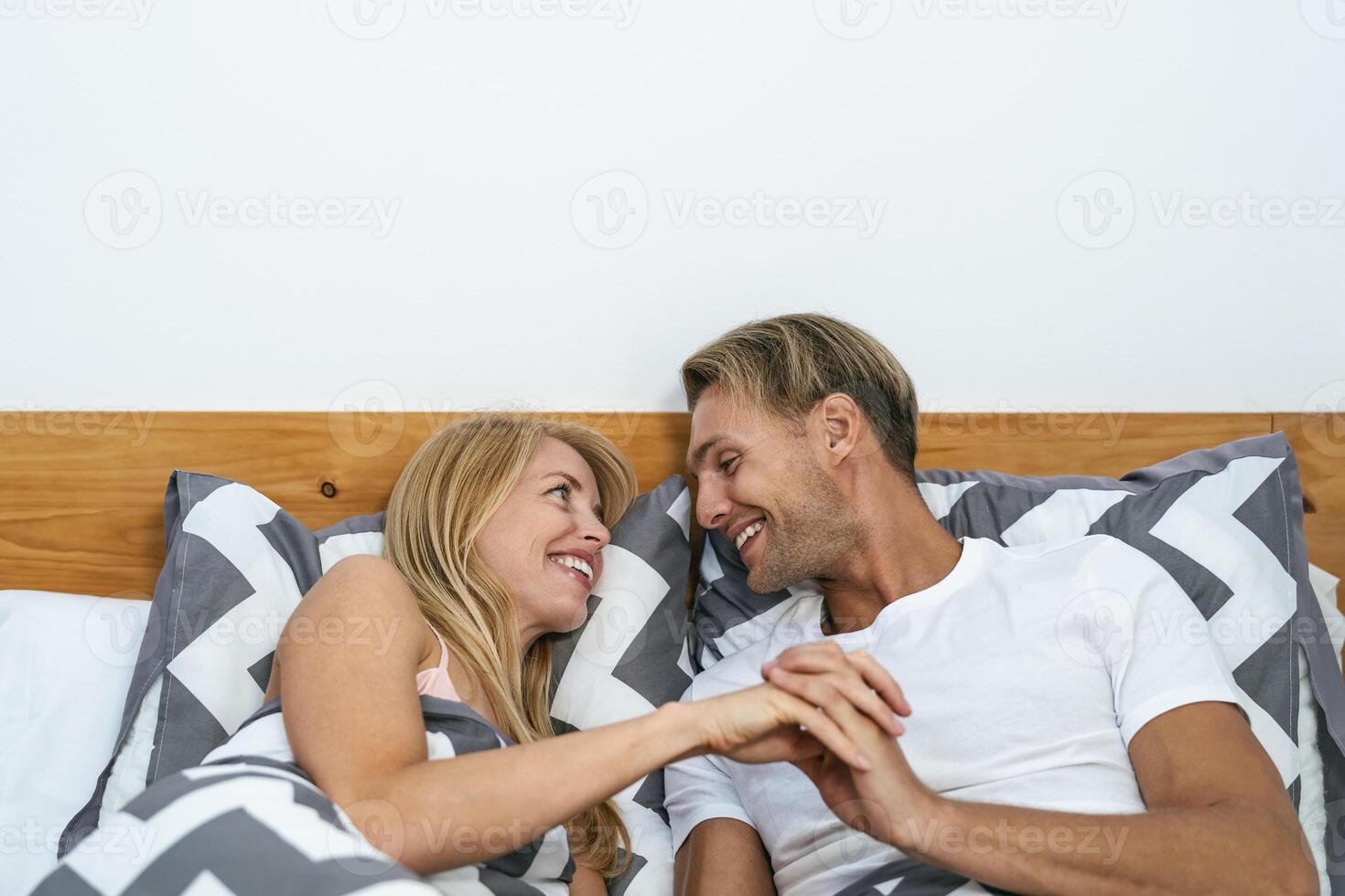 Happy smiling couple lying on bed having tender moments - Young people love and relationship concept photo