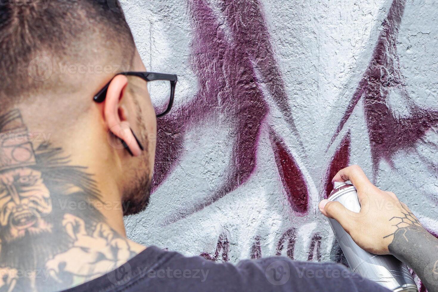 calle pintada artista pintura con un color rociar lata un oscuro monstruo cráneo pintada en el pared en el ciudad al aire libre - cerca arriba mano pinturas - urbano, estilo de vida contemporáneo calle Arte concepto foto