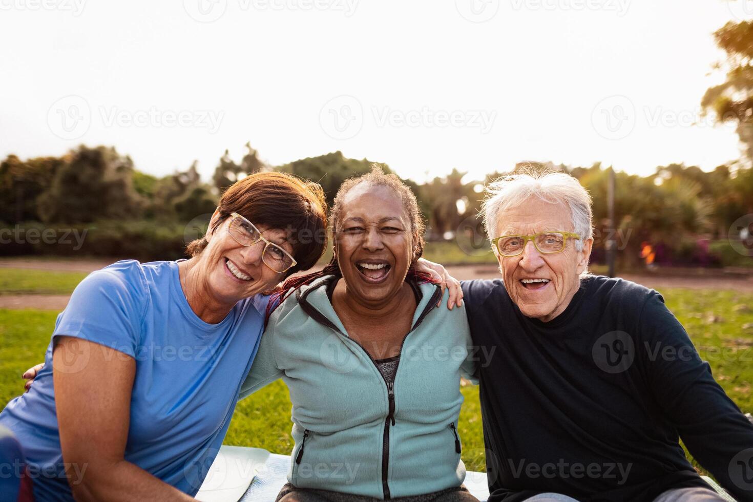 Happy multiracial senior friends having fun smiling at the camera after training activities in the park photo