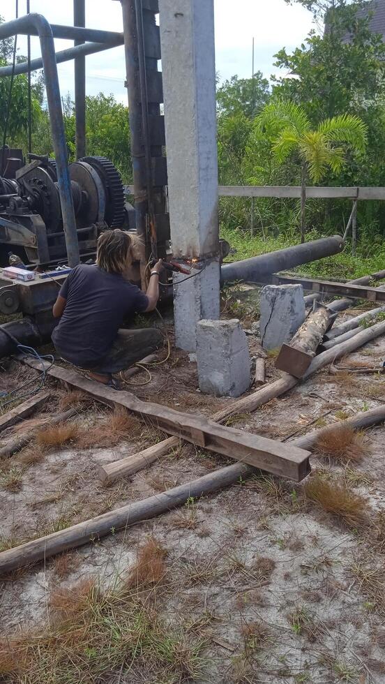 Workers is welding metal parts of concrete pile photo