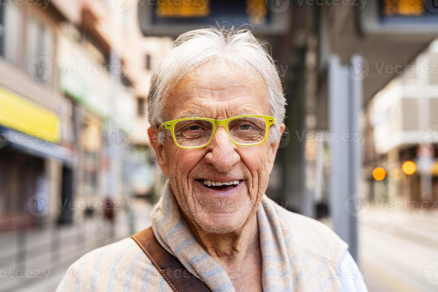 Happy senior man smiling in front of camera while waiting at tram station in the city photo