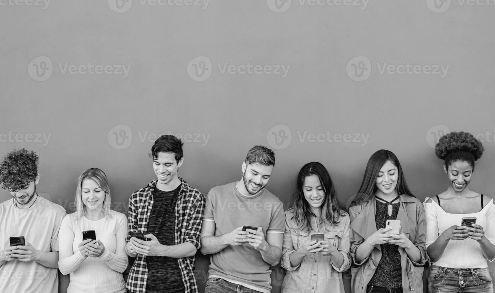 Young multiracial group of friends using mobile smartphone outdoor - Youth people and technology addiction concept - Black and white editing photo