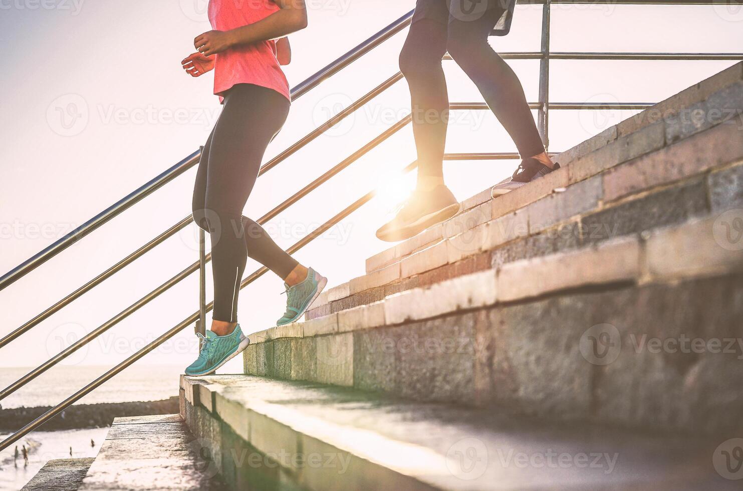 ver de corredores piernas teniendo un rutina de ejercicio sesión en ciudad escalera al aire libre - cerca arriba de personas corriendo a puesta de sol - deporte, correr, salud estilo de vida concepto - atención en Zapatos en izquierda foto