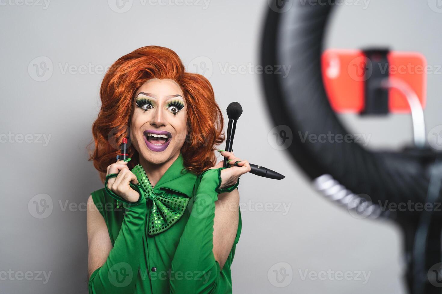 Happy drag queen social influencer vlogging online a makeup class with smartphone cam and ring led photo