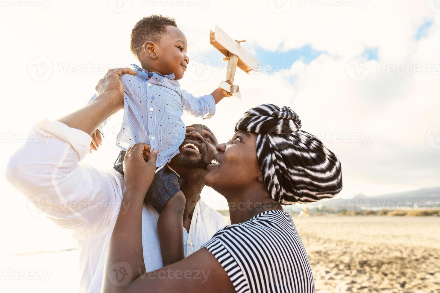 Happy African family having fun on the beach during summer vacation - Parents love and unity concept photo