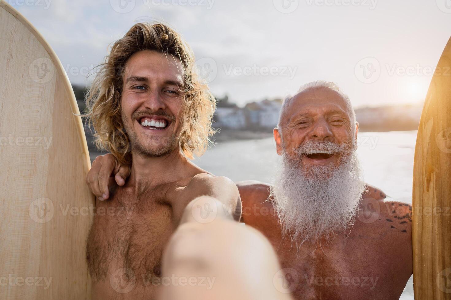 Happy fit surfers taking selfie while having fun surfing together at sunset time - Extreme sport lifestyle and friendship concept photo