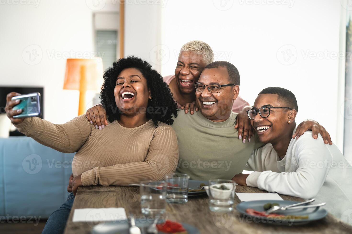 contento negro familia teniendo divertido tomando selfie con móvil teléfono inteligente leva mientras teniendo almuerzo a hogar foto