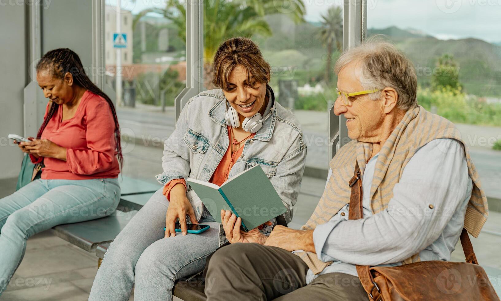 Multiracial people reading a book while waiting at tram station in the city photo