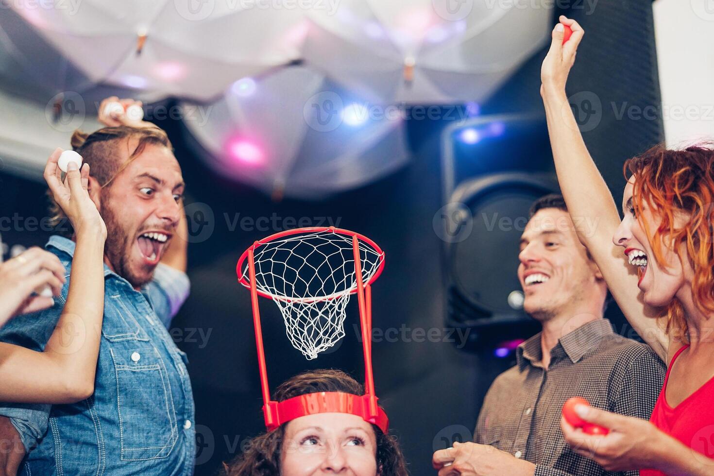 Group of friends playing funny basketball games inside a pub cocktail bar - Young happy people having fun hangout in the weekend - Friendship, entertainment and youth lifestyle concept photo