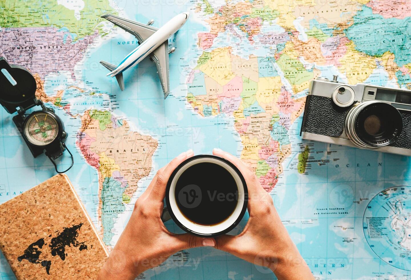 Top view of young woman planning her vacation using world map while drinking coffee - Tourist pointing the next travel destination - Concept of adventure, tourism, and traveling people lifestyle photo