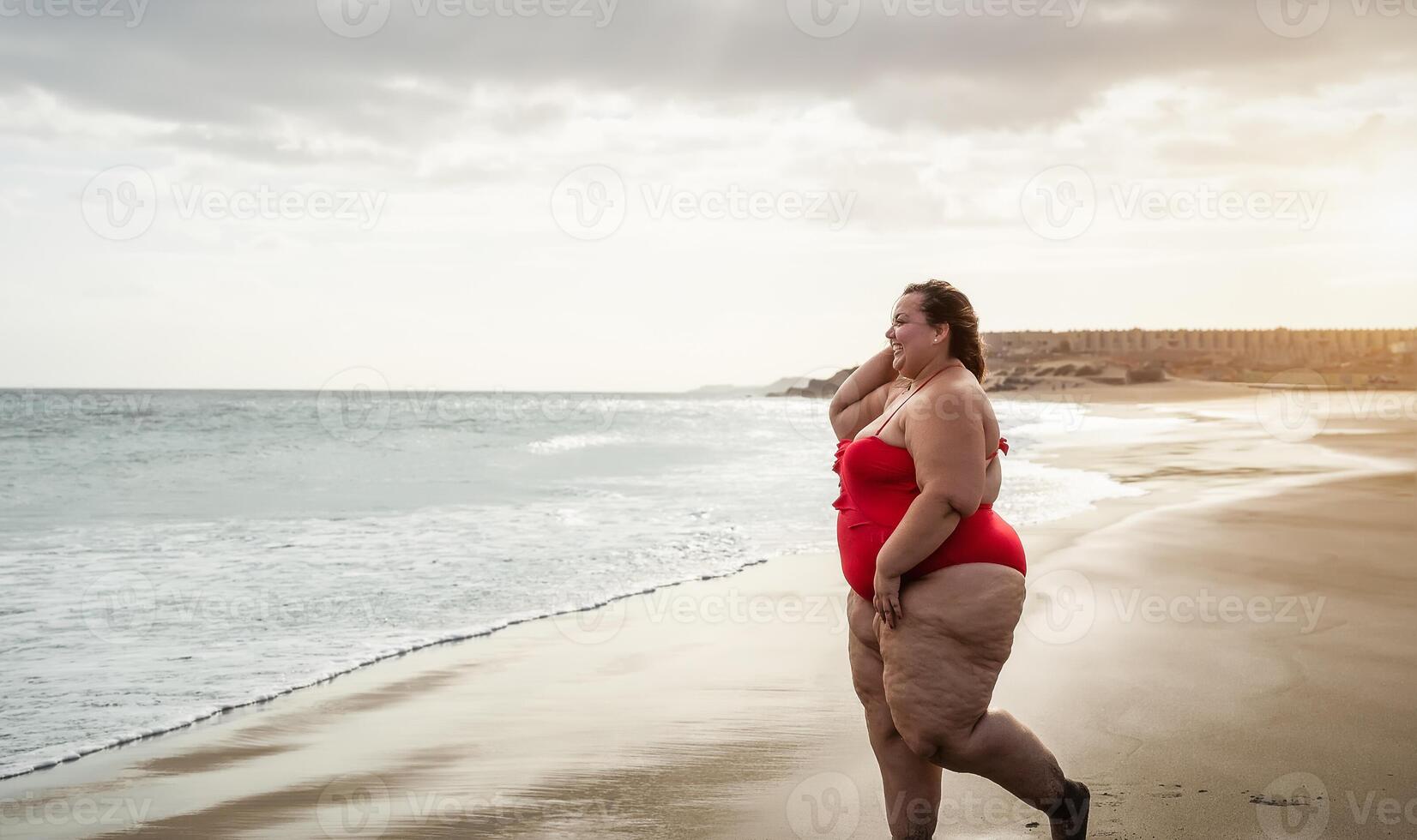 Happy plus size woman having fun walking on tropical beach during summer time - Curvy confident people lifestyle concept photo