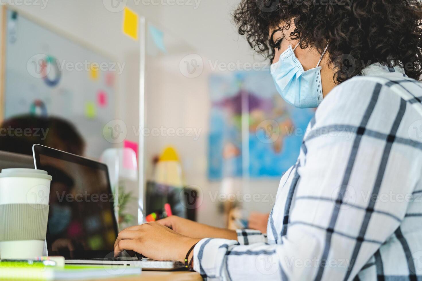 Young people in co-working creative space wearing surgical mask protection and keeping social distance to avoid corona virus spread - Health care and business technology concept photo