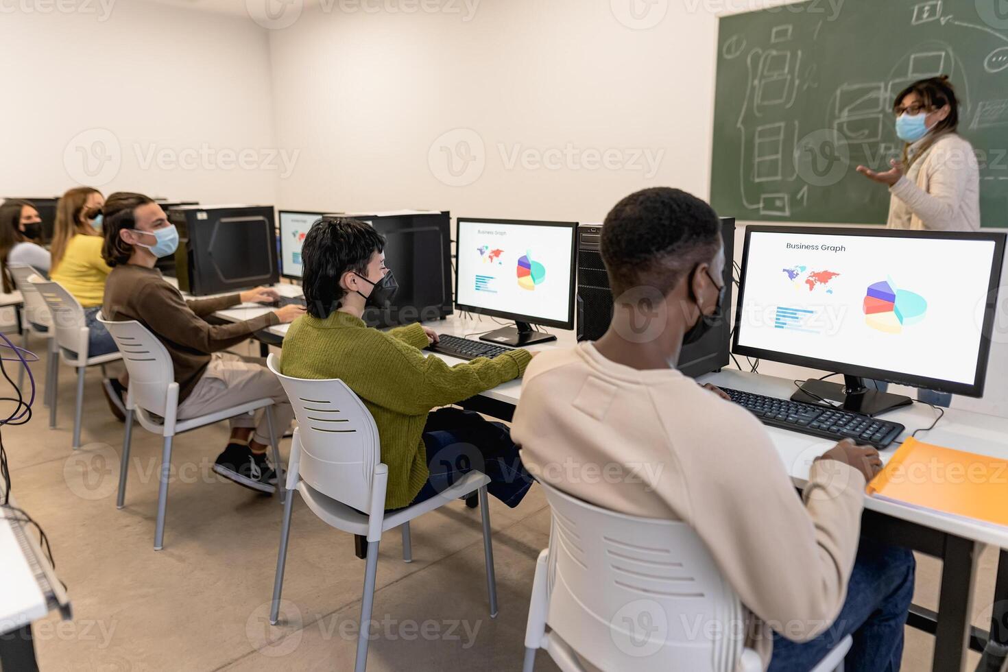 Young students listening a lesson in high school while wearing face mask during corona virus pandemic - Education and technology concept photo